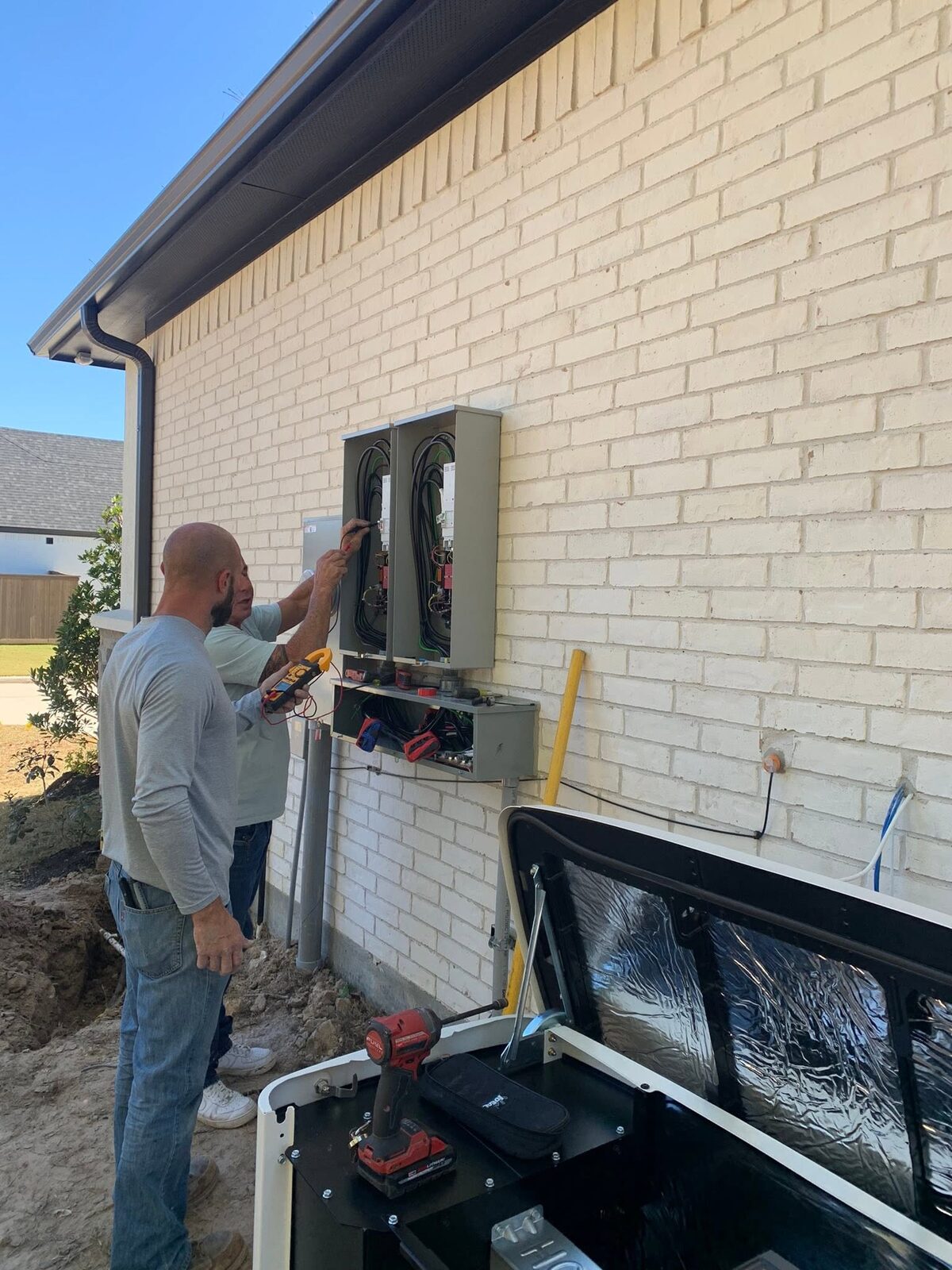 Electricians completing transfer switch wiring for a standby generator